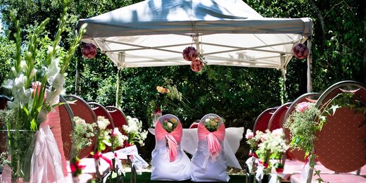 Mariage en plein air entouré d'hébergements insolites, chaises rouges décorées, nature luxuriante. Auberge de la Tuilière
