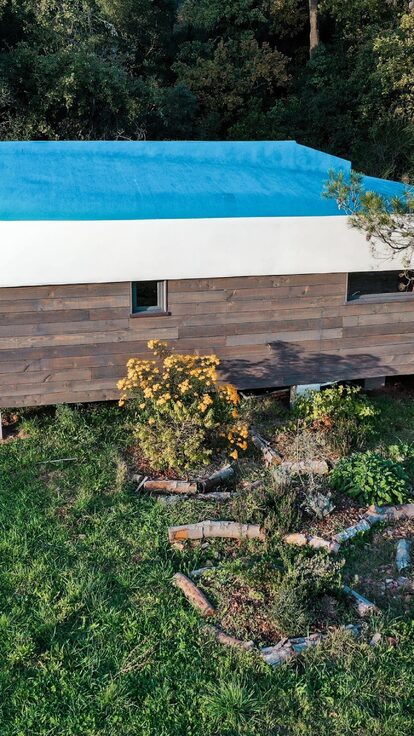 Cabane perchée insolite au toit-bateau, tipyramide végétale et fleurs jaunes, nature préservée. Auberge de la Tuilière