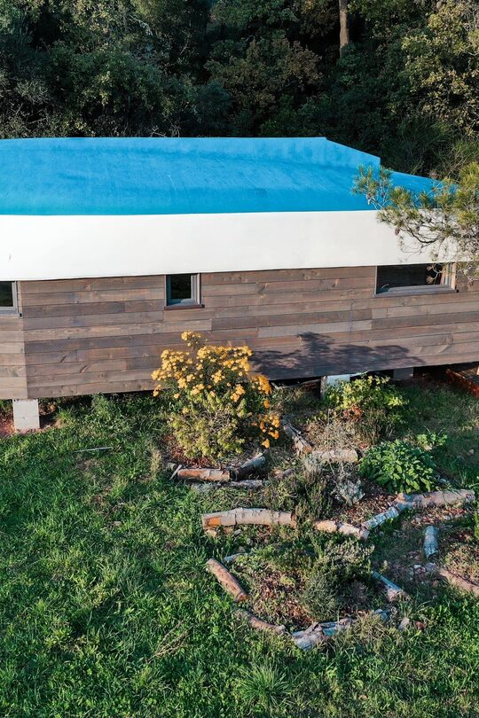 Cabane perchée insolite au toit-bateau, tipyramide végétale et fleurs jaunes, nature préservée. Auberge de la Tuilière