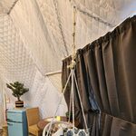 Hébergement insolite : fauteuil suspendu, coussins, plaid rose, bonsaï et frigo rétro sur murs matelassés. Auberge de la Tuilière