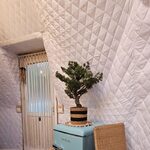 Frigo rétro bleu et fauteuil en osier dans hébergement insolite, murs quiltés, bonsaï posé dessus. Auberge de la Tuilière
