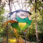 Cabane perchée design, grandes baies vitrées, nichée parmi les arbres avec escalier en colimaçon. Auberge de la Tuilière