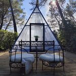 Tipyramide vitrée sur terrasse bois, assises cosy, intimité en pleine nature pour un séjour insolite. Auberge de la Tuilière