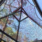 Plafond vitré géométrique, filets colorés, arbres et ciel : séjour insolite en pleine nature. Auberge de la Tuilière