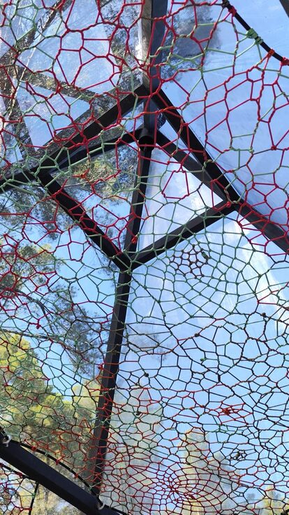 Plafond vitré géométrique, filets colorés, arbres et ciel : séjour insolite en pleine nature. Auberge de la Tuilière
