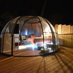 Dôme transparent sur terrasse bois, ambiance chaleureuse, nature et confort pour séjour insolite nocturne. Auberge de la Tuilière