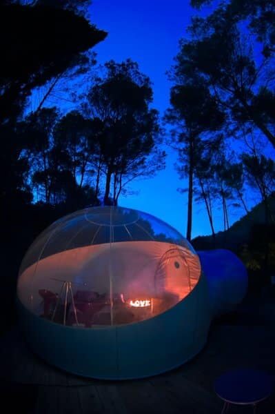 Bulle transparente illuminée LOVE, cabane insolite nichée sous les arbres, ambiance cosy et nature. Auberge de la Tuilière