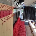 Bus insolite bois et velours, ambiance cabane perchée, grande table, lumière naturelle éclatante. Auberge de la Tuilière