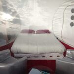 Nuit insolite en bulle transparente : lit douillet, fauteuils argentés, vue nature façon cabane perchée. Auberge de la Tuilière