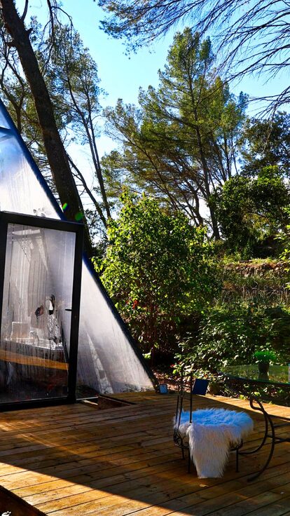Tipyramide transparente sur terrasse bois, chaises cosy dans la verdure, parenthèse insolite et sereine. Auberge de la Tuilière