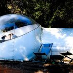 Tente bulle transparente sur terrasse bois, cadre verdoyant, expérience insolite alliant confort et nature. Auberge de la Tuilière
