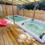 Campalune insolite avec bain à remous sur terrasse bois, piscine et chaises longues colorées au soleil. Auberge de la Tuilière