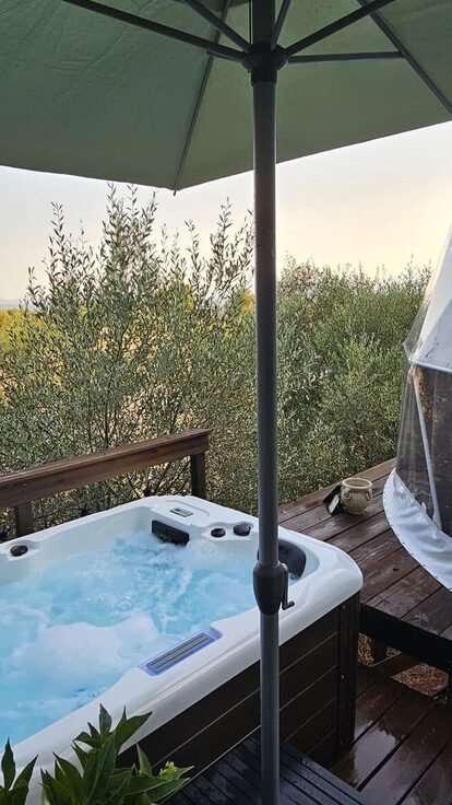 Bain à remous sur terrasse bois, dôme blanc insolite, arbres et guirlandes lumineuses, nature paisible. Auberge de la Tuilière