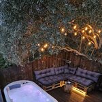 Terrasse bois, bain chaud, canapé rustique : confort unique pour une pause insolite en pleine nature. Auberge de la Tuilière