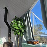 Hébergement insolite : pièce cosy, poêle à bois, plante verte, ambiance unique et lumineuse. Auberge de la Tuilière