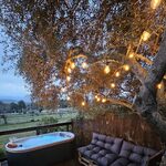 Terrasse en bois avec bain bouillonnant, assises palettes, guirlande suspendue près d'hébergements insolites. Auberge de la Tuilière