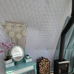Cabane perchée avec coiffeuse menthe, orchidée et poêle à bois sur fond de murs clairs quiltés. Auberge de la Tuilière