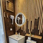 Salle de bain moderne au charme campalune, sol à motifs, vasque blanche, miroir rond lumineux. Auberge de la Tuilière