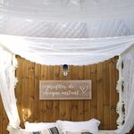 Lit douillet, rideaux fleuris et lumière douce dans une campalune unique nichée en pleine nature. Auberge de la Tuilière