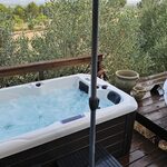 Bain à remous sur terrasse bois, près cabane perchée, nature verdoyante, hébergement insolite. Auberge de la Tuilière