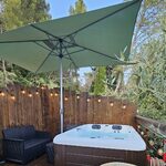 Bain chauffant couvert sur terrasse bois, salon cosy, guirlandes lumineuses et verdure apaisante. Auberge de la Tuilière